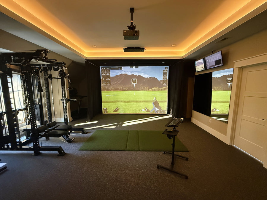 Indoor golf simulator setup in a room with a screen displaying a golf course.