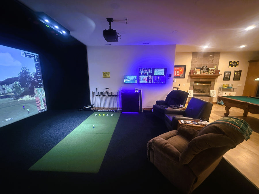 Indoor golf simulator room with a large screen displaying a golf round, pool table, and sports memorabilia.