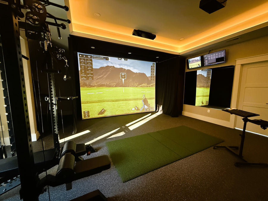 Golf simulator setup in a room with multiple screens displaying golf game graphics.