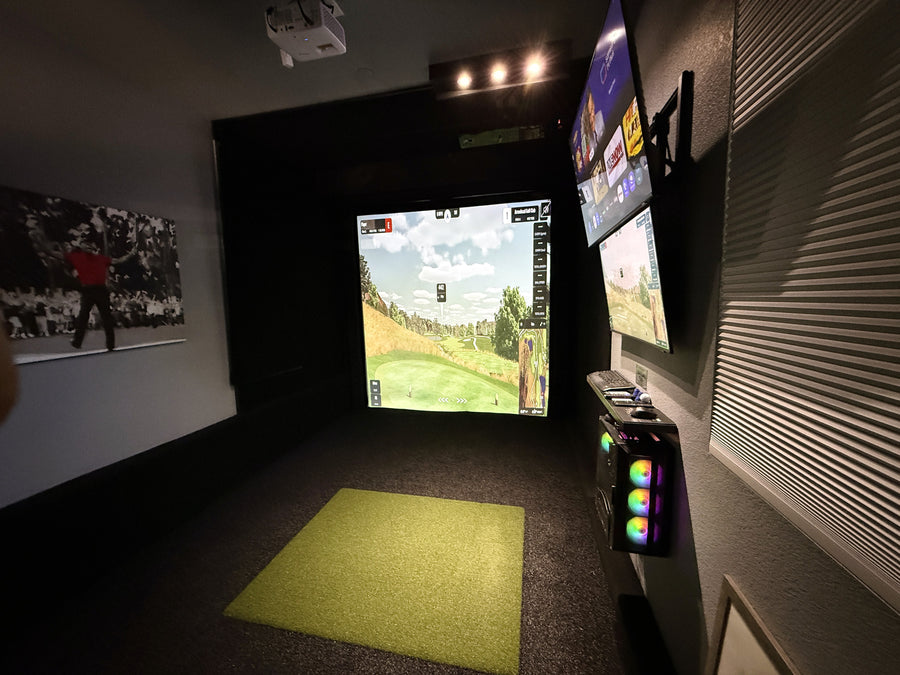 Indoor golf simulator setup with multiple screens displaying a golf course.