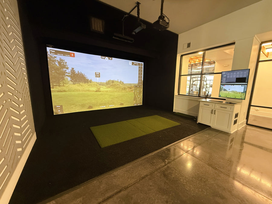 Indoor golf simulator setup with two screens displaying a golf course.
