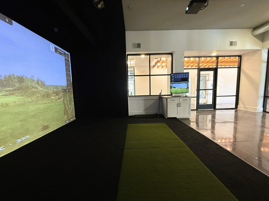Golf simulator room with large screen displaying a golf course.