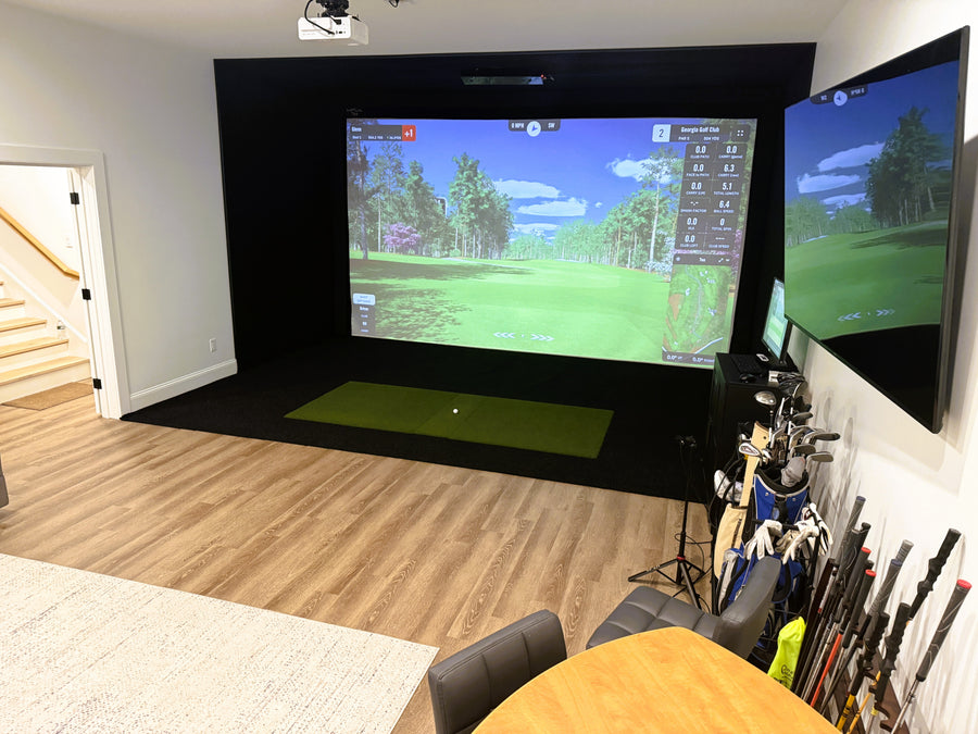 Home golf simulator setup with two screens displaying a golf course.