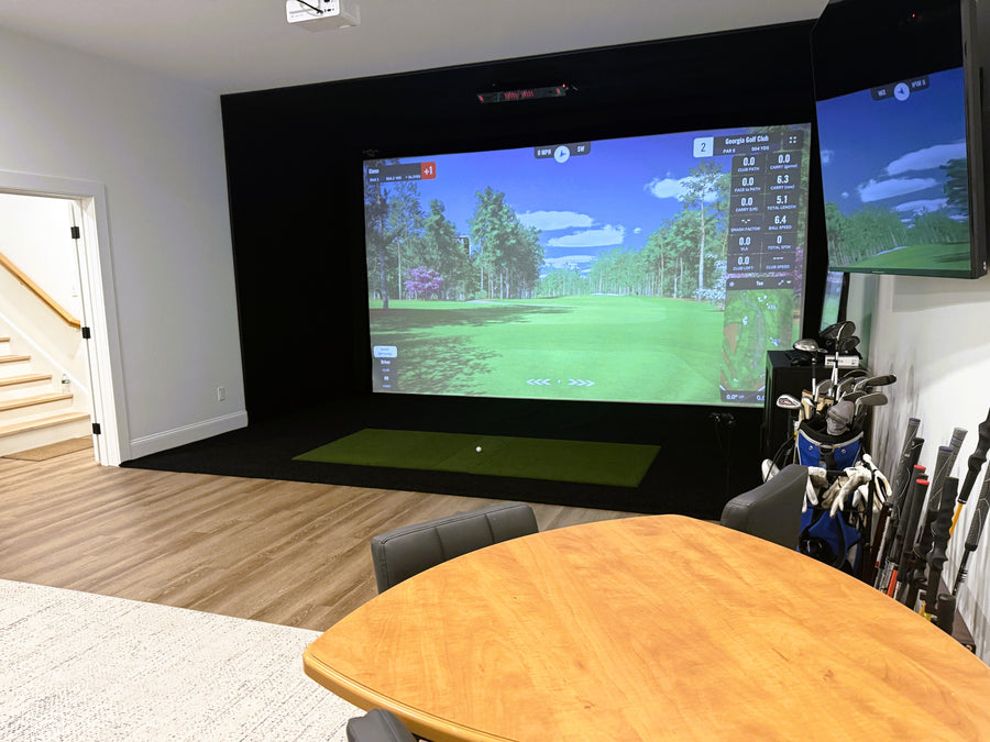 Golf simulator setup in a room with a large screen displaying a golf course.