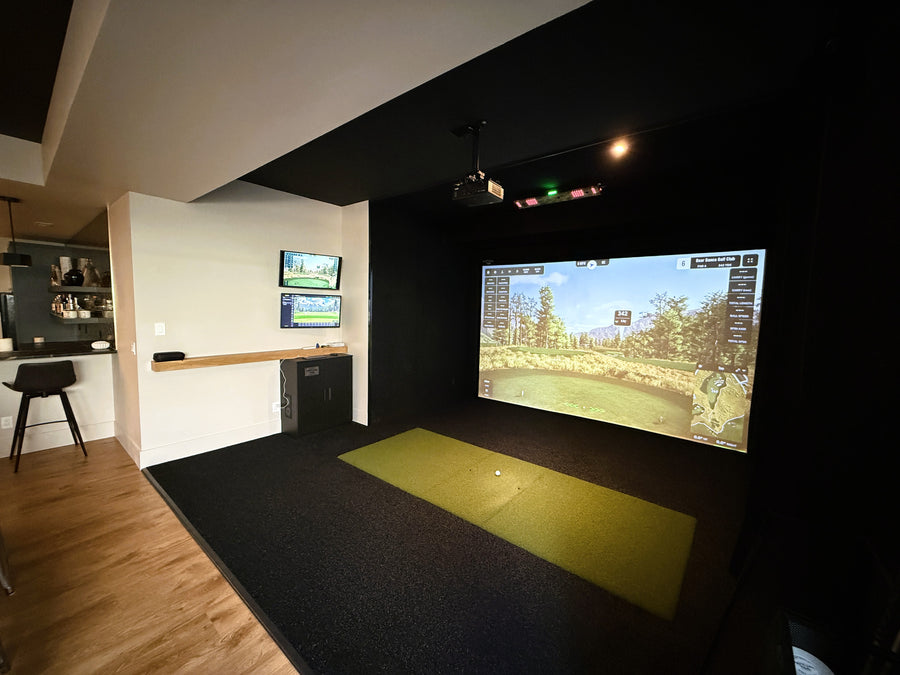 Indoor golf simulator setup with a large screen displaying a golf course.