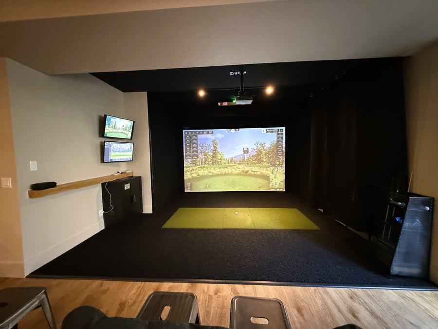 Indoor golf simulator setup with multiple screens in a room.