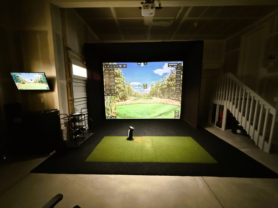 Indoor golf simulator setup with two screens displaying a golf course.