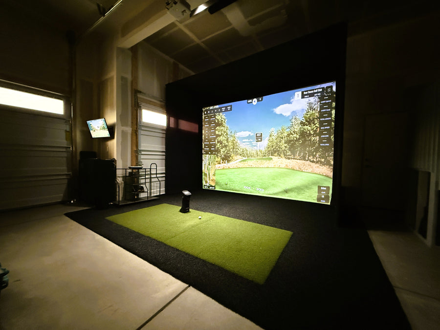 Indoor golf simulator setup with screen displaying a golf course.