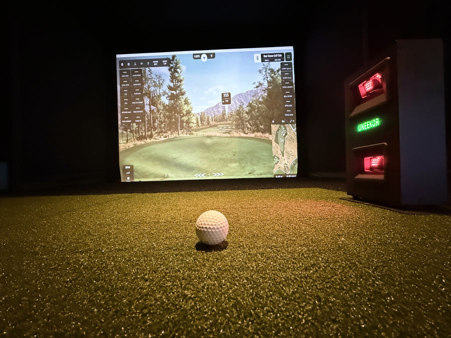 Golf ball on a golf simulator with a screen displaying a golf course.