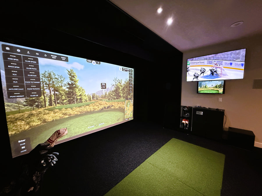 Golf simulator setup with large screen and additional TV in a room.