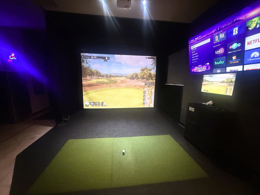 Custom golf simulator with screen displaying golf round and green turd on the floor.