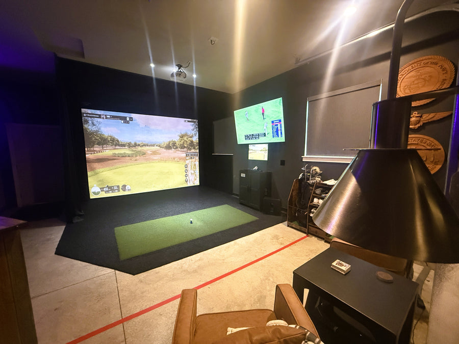 Custom golf simulator with screen displaying golf round and green turd on the floor.