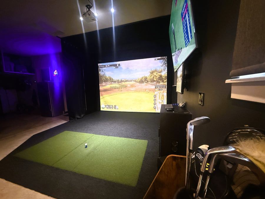 Custom golf simulator with screen displaying golf round and green turd on the floor.