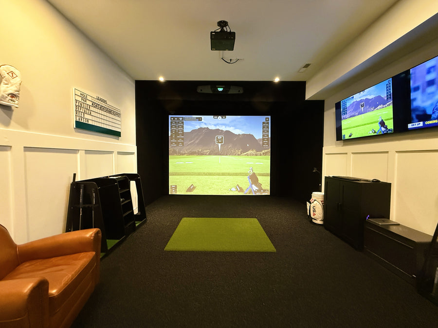 Indoor golf simulator setup with a large screen displaying a video game, surrounded by furniture.