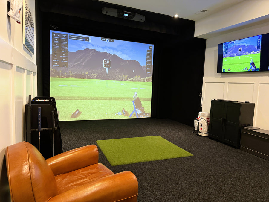 Golf simulator setup in a room with a large screen displaying a golf course.