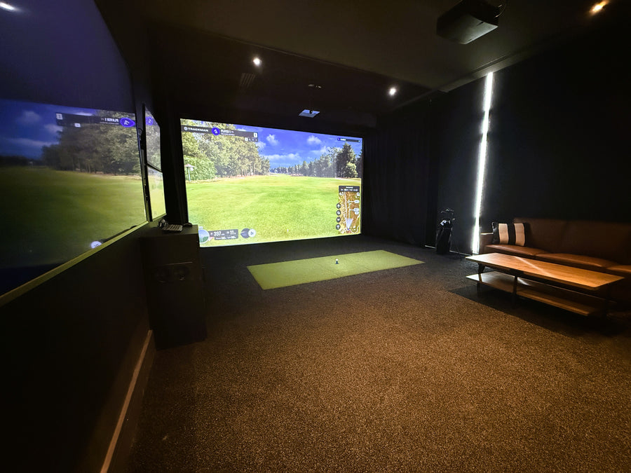 Indoor golf simulator setup with two screens displaying a golf course.