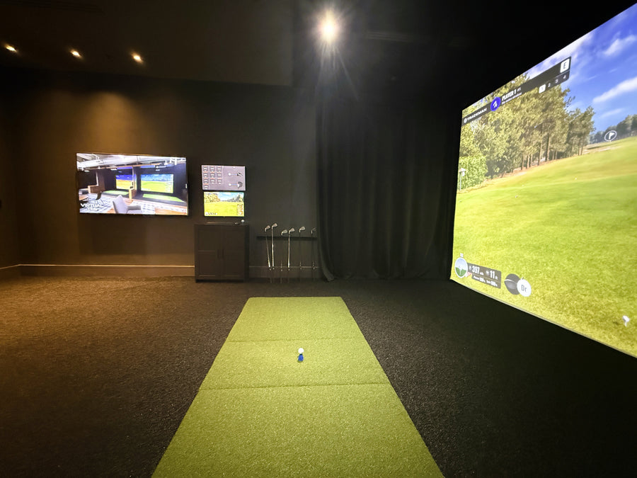 Indoor golf simulator with multiple screens displaying a golf course.