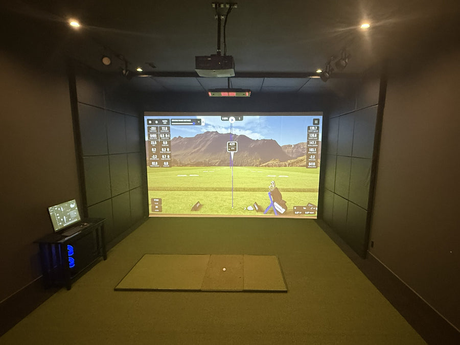 Indoor golf simulator setup with projection screen and equipment.