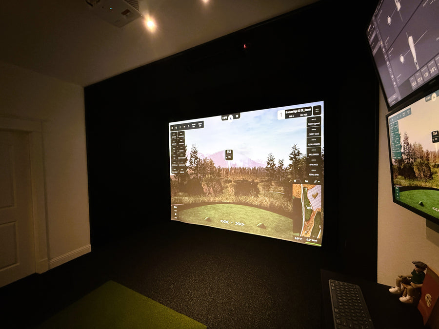 Golf simulator setup with multiple screens in a dark room