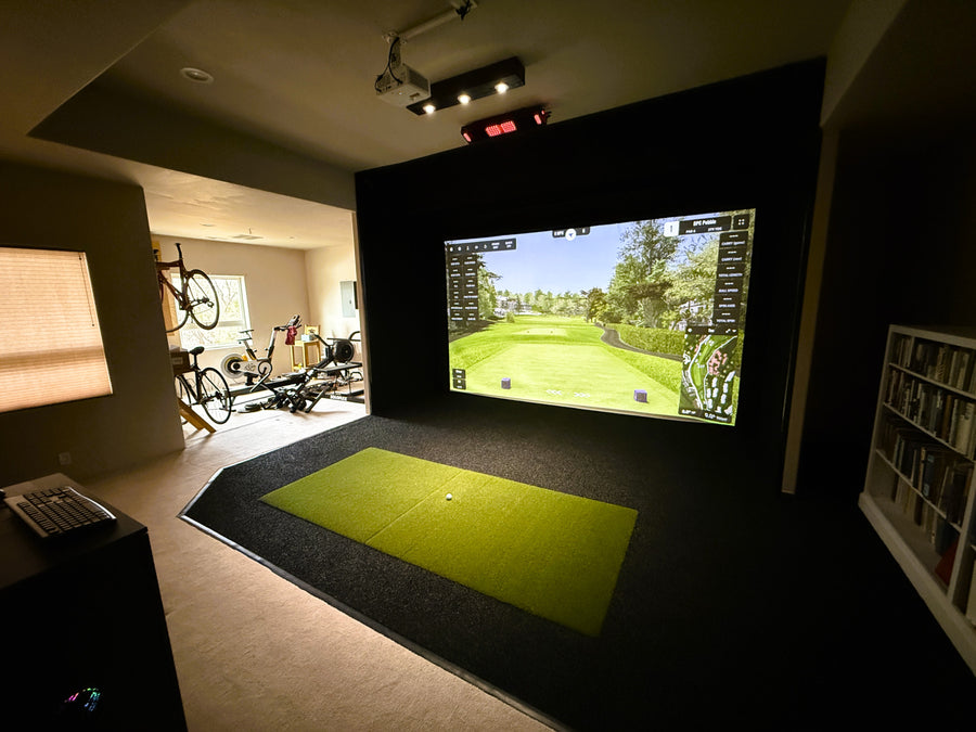 Indoor golf simulator setup with screen displaying a golf course.