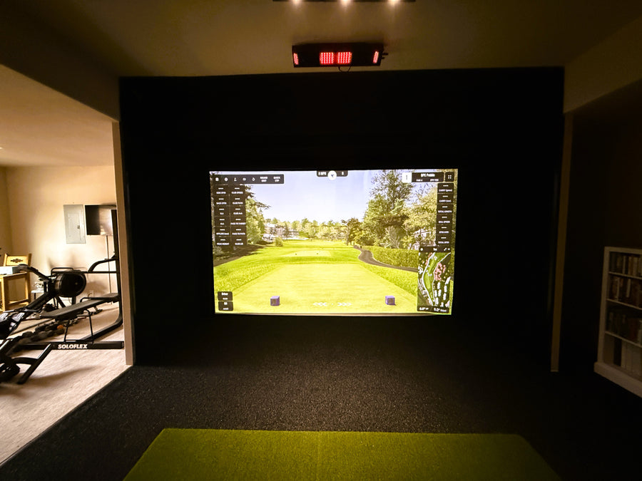 Indoor golf simulator setup with a screen displaying a golf course.