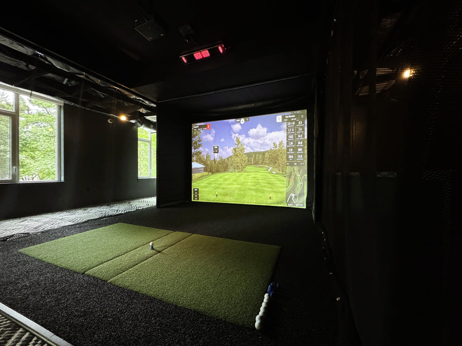 Indoor golf simulator setup with a screen displaying a golf course.