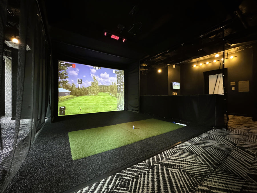 Indoor golf simulator setup with a screen displaying a golf course.