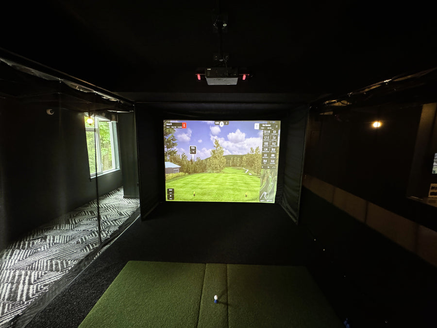 Indoor golf simulator setup with screen displaying a golf course.