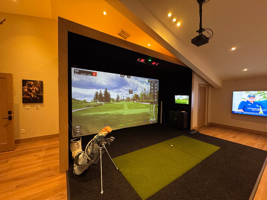 Indoor golf simulator setup with large screen displaying a golf course.
