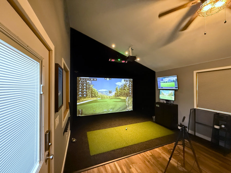 Indoor golf simulator setup with two screens displaying a golf course.