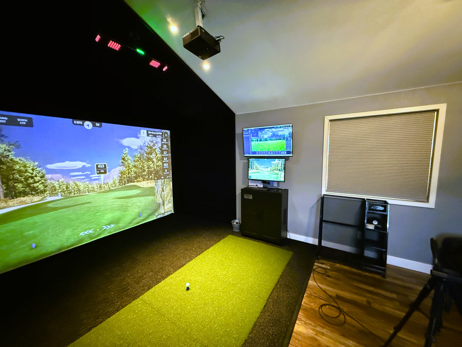 Indoor golf simulator setup with multiple screens in a room.