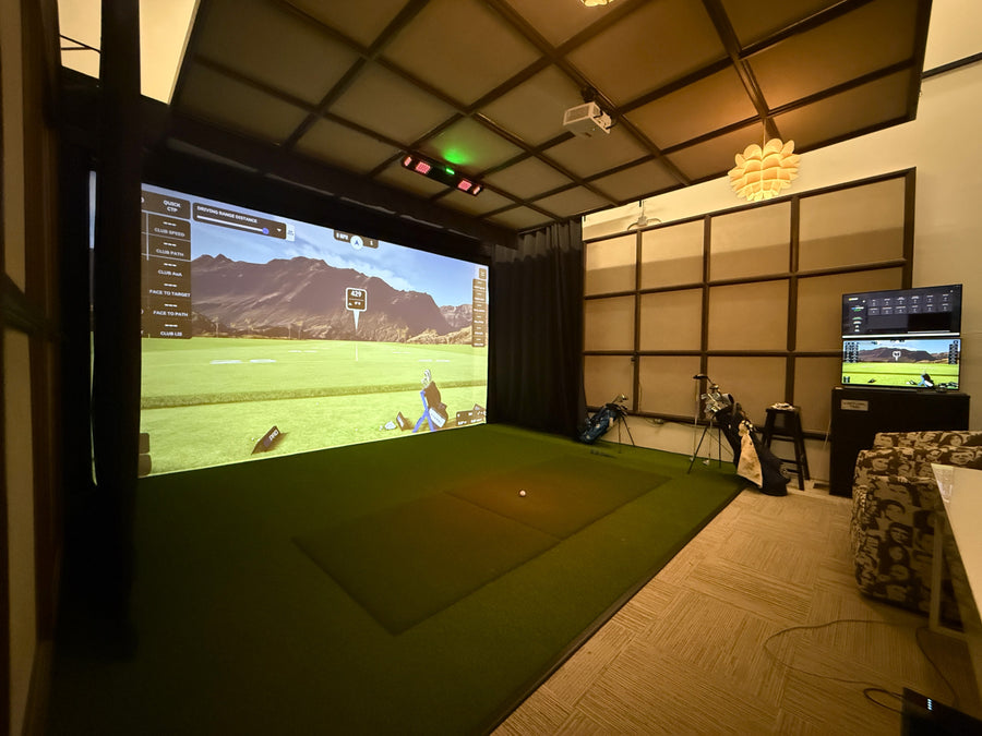 Indoor golf simulator setup with two screens displaying a golf course.