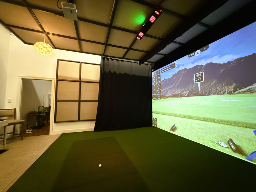 Indoor golf simulator setup with a large screen displaying a virtual golf course.