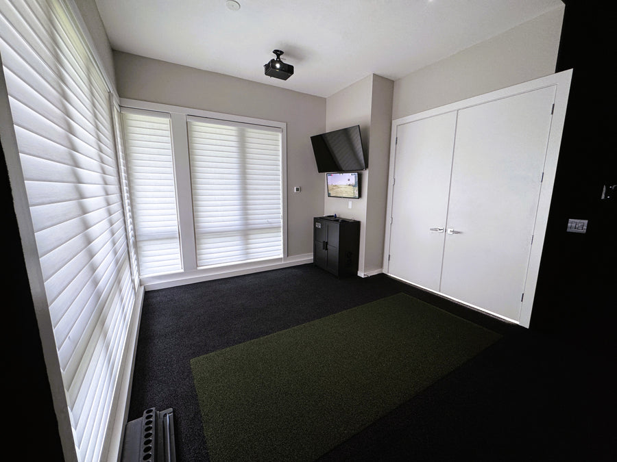 Corner of golf simulator room with Tv's mounted to the wall and projector to the ceiling. 