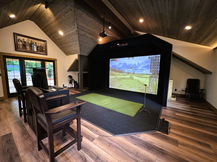 Golf simulator setup in a home entertainment room with a large screen displaying a golf course.