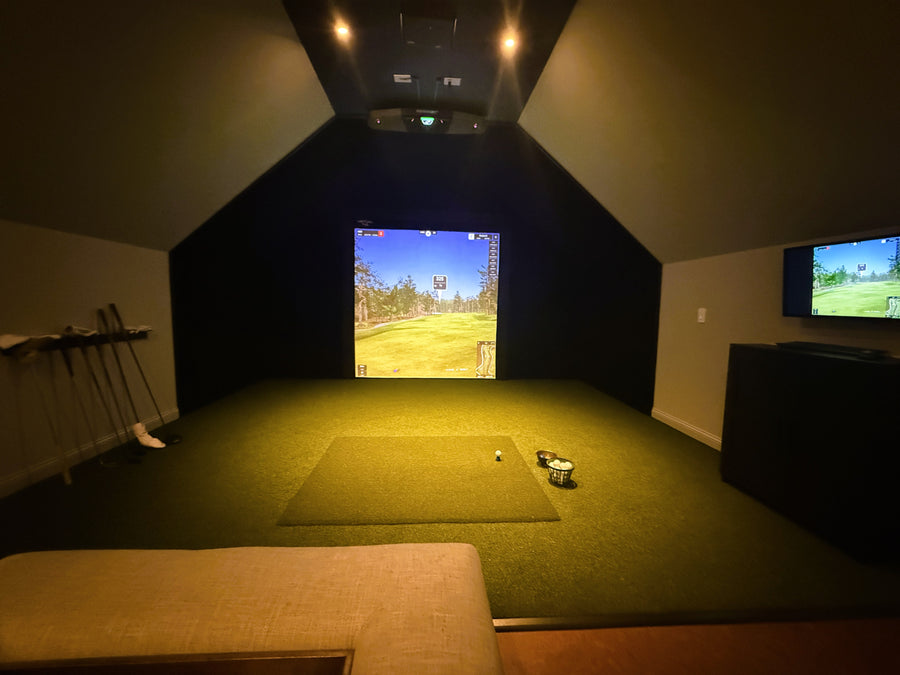 Indoor golf simulator setup with two screens displaying a golf course.