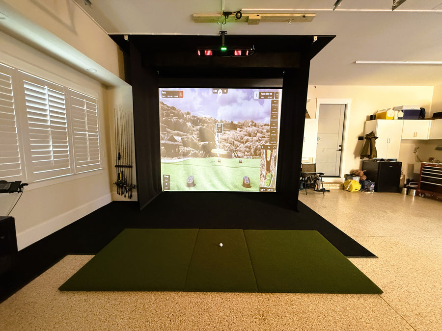 Indoor golf simulator setup with screen displaying a golf course.