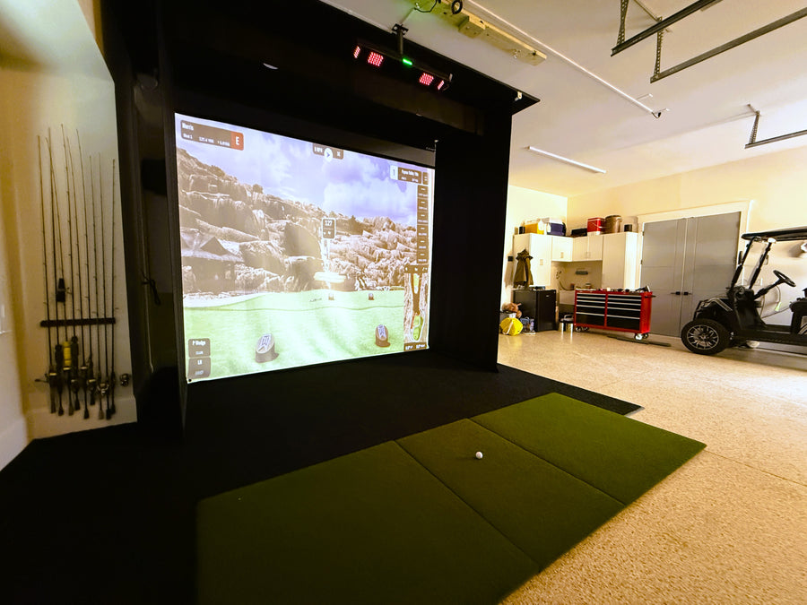 Golf simulator setup in a home garage with screen displaying golf course.
