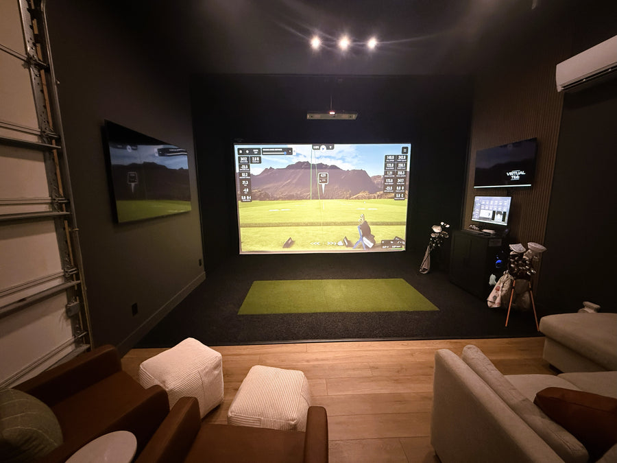 Indoor golf simulator setup in a room with multiple screens and chairs.