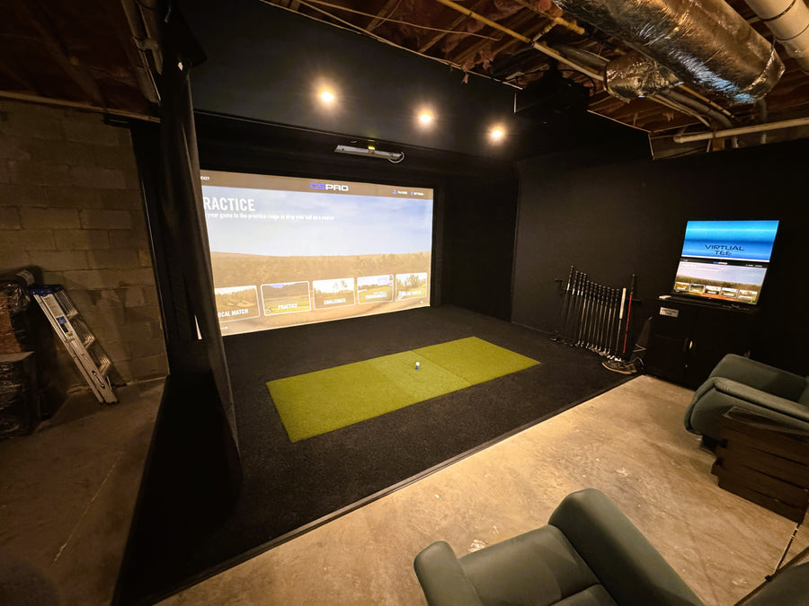 Indoor golf simulator setup in a room with a screen displaying a golf course.