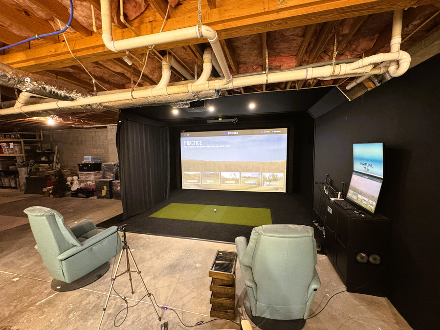 Indoor recreational area with a large screen displaying a golf game, surrounded by chairs and golf equipment.