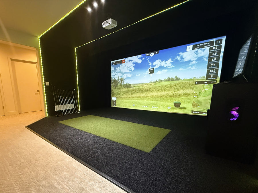 Indoor golf simulator setup with a large screen displaying a golf course.
