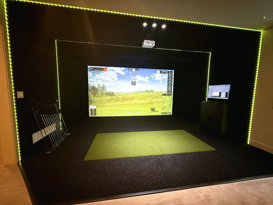 Indoor golf simulator setup with screen displaying a golf course.