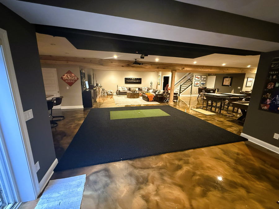 Golf simulator setup in a home entertainment room with a large screen and gaming chairs.