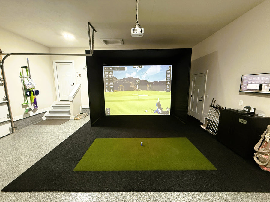 Indoor golf simulator setup in a room with a screen displaying a golf course.