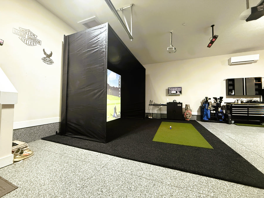 Indoor golf simulator setup in a garage with a screen and golf club.