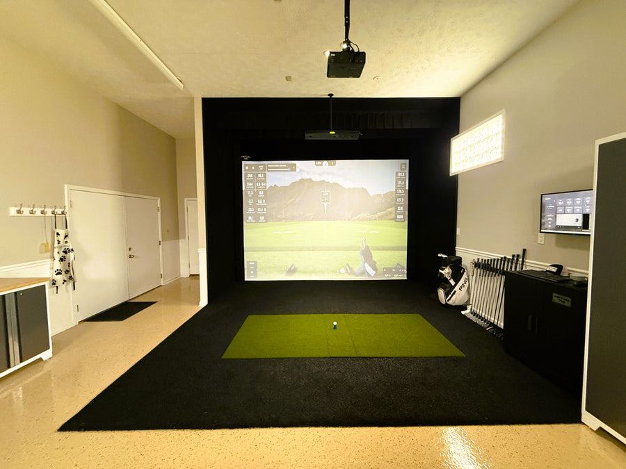 Indoor golf simulator setup with a screen displaying a golf course.