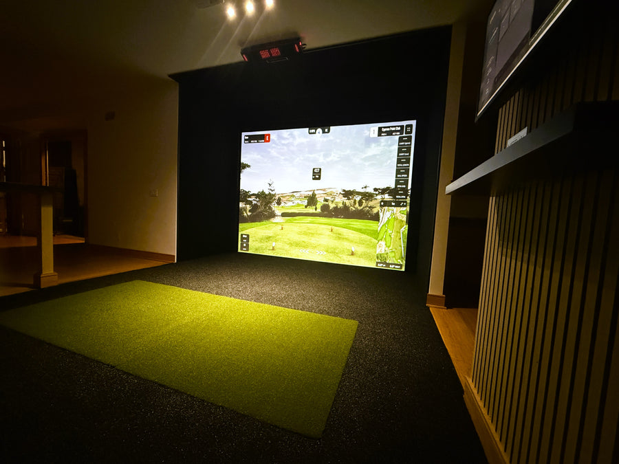 Indoor golf simulator setup with screen displaying a golf course.