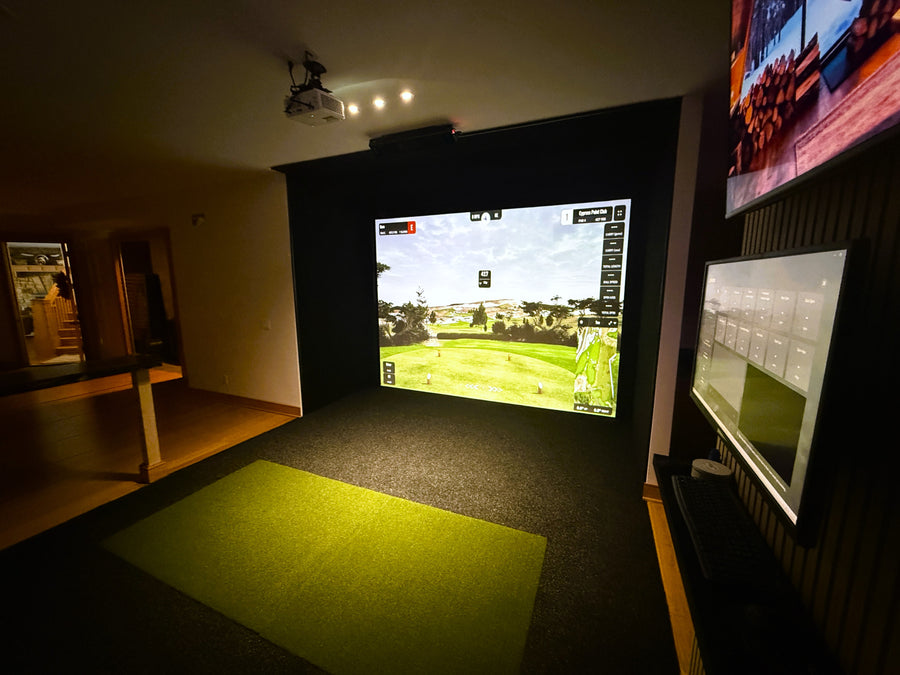 Indoor golf simulator setup with screen displaying a golf course.