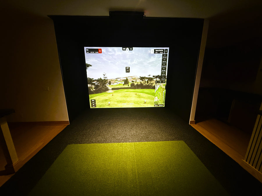 Indoor golf simulator setup with a screen displaying a golf course.